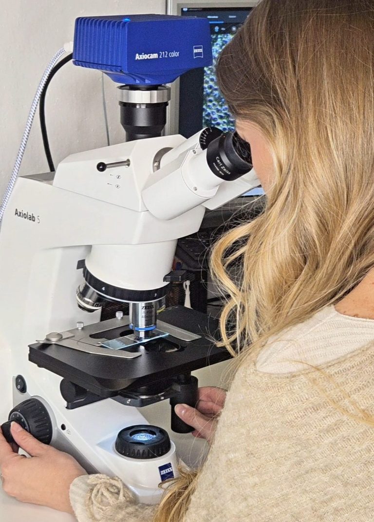 Anna Gassner von Klar gesund schaut durch das Dunkelfeldmikroskop und untersucht Blutproben.