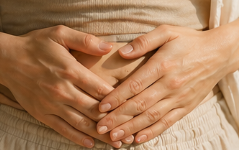Hände formen ein Herz über dem Bauch einer Person.